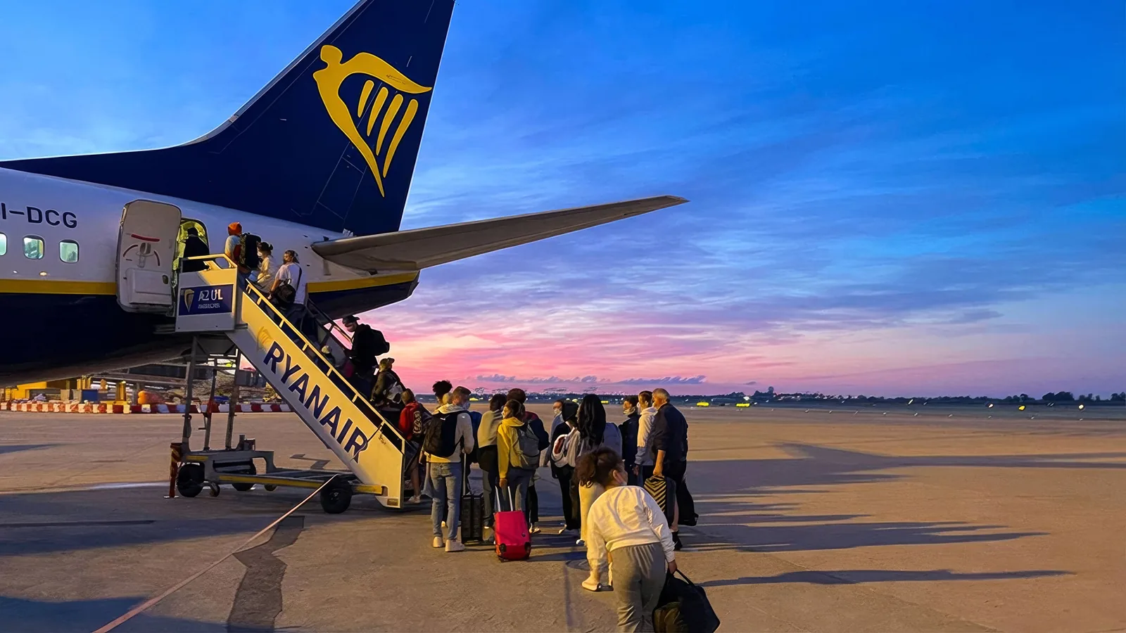 Travelers board a Ryanair plane at sunrise, connecting for website design.